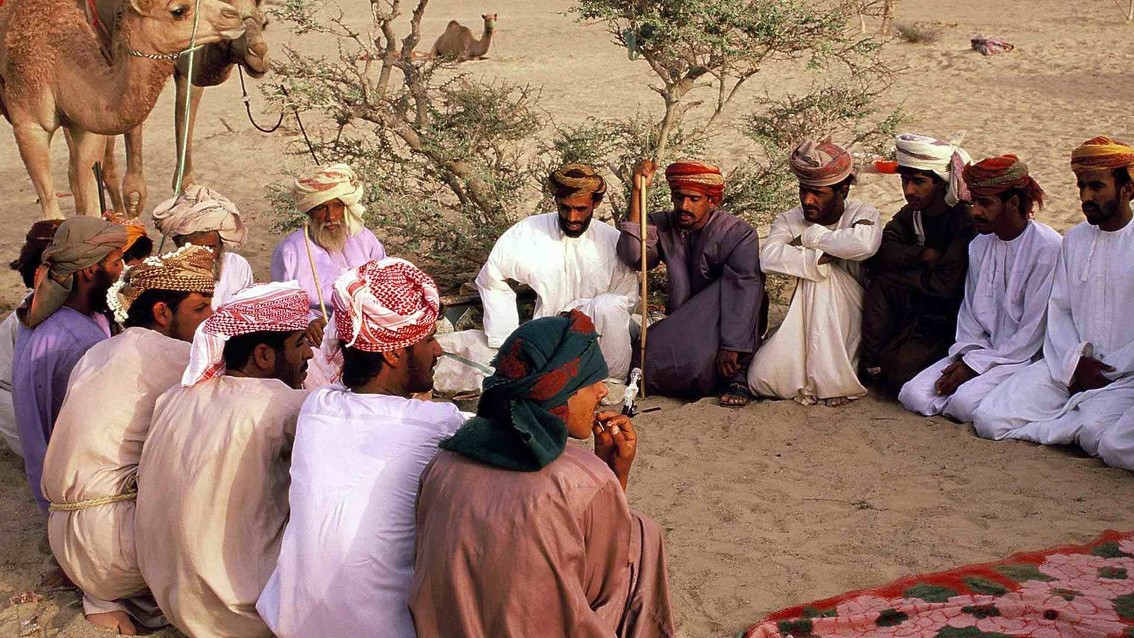 Omani hospitality traditions: men gathered in a desert, embracing Bedouin culture.