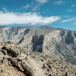 A breathtaking view of Jebel Shams, Oman's highest peak, showcasing rugged rocky cliffs and a clear blue sky.