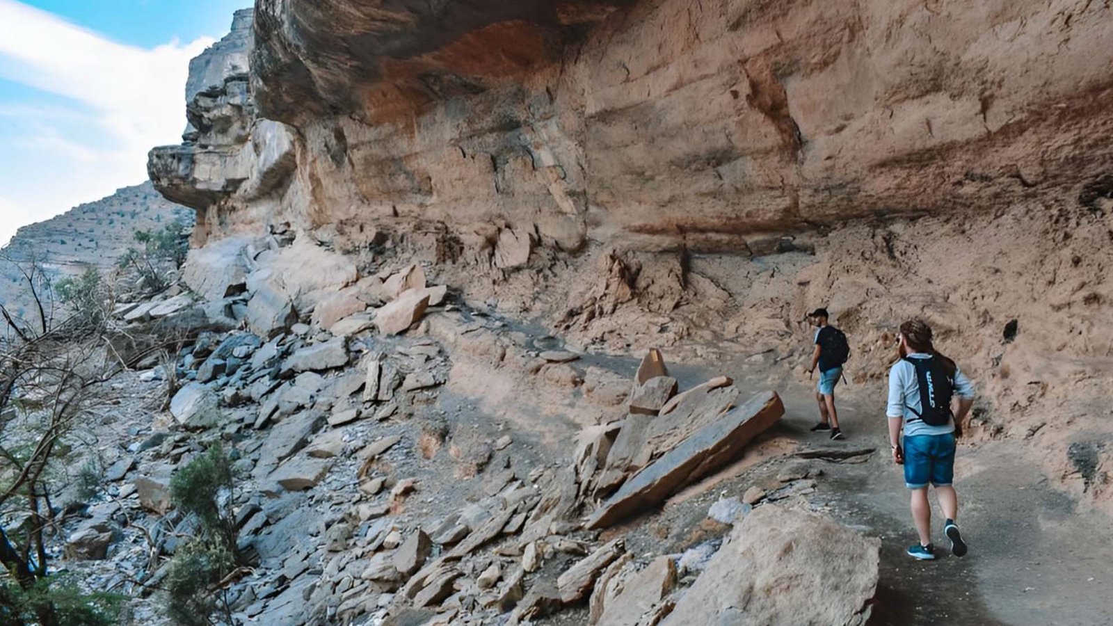 Hikers navigating the rocky Balcony Walk trail at Jebel Shams, Oman.