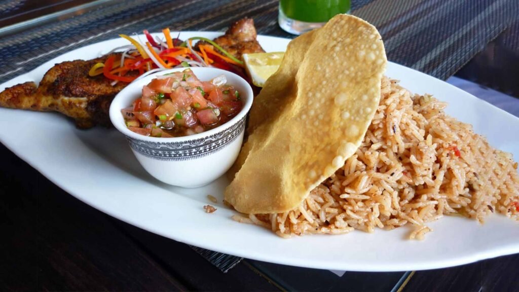 Plate of traditional Omani cuisine featuring spiced rice, grilled chicken, crispy bread, and a side of fresh salsa, showcasing the rich flavors of Oman.