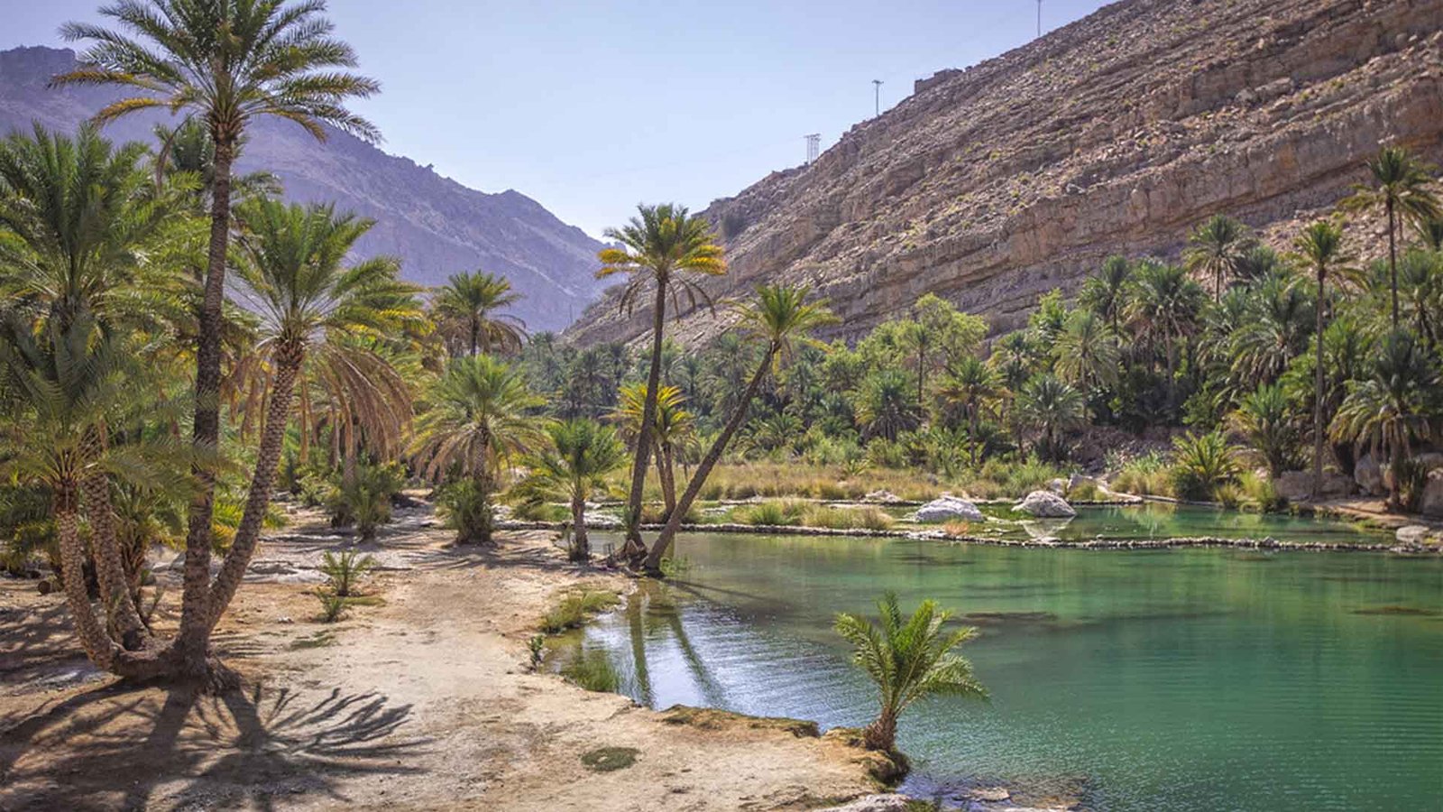 Visitors exploring the stunning sandy dunes and shoreline of Oman, highlighting the importance of a well-prepared Oman travel packing list, especially for sun protection.