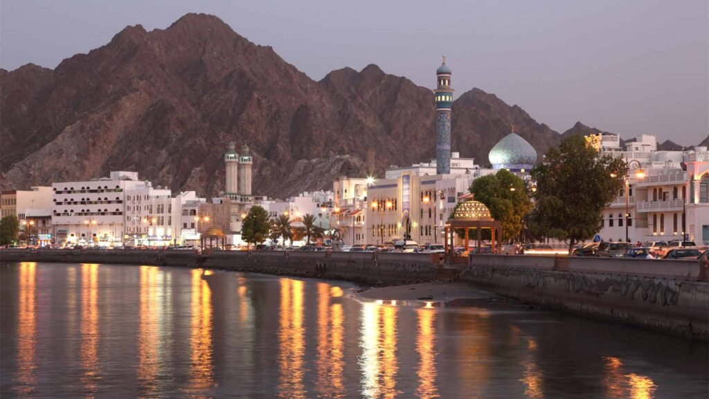 Traditional Omani architecture and illuminated buildings against a backdrop of mountains, showcasing one of the top Oman tourist attractions.