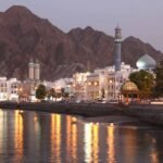 Traditional Omani architecture and illuminated buildings against a backdrop of mountains, showcasing one of the top Oman tourist attractions.