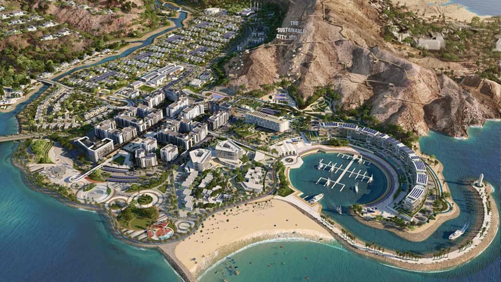 Aerial view of a sustainable city project by the coast in Oman, showcasing modern eco-friendly buildings, green spaces, and marina, representing eco-tourism in Oman.