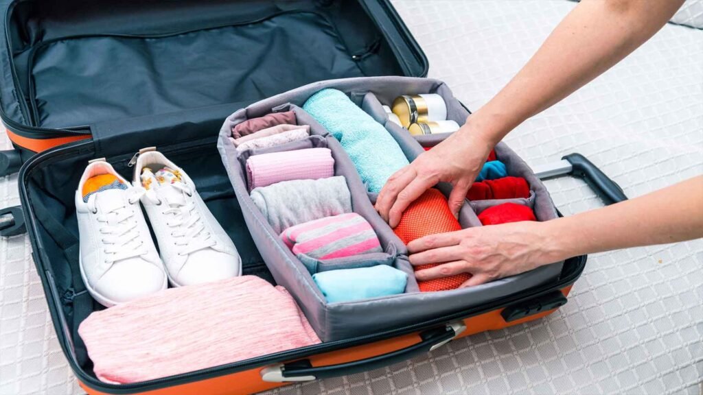 Person organizing a well-packed suitcase with neatly rolled clothes, shoes, and travel essentials, representing an efficient Oman travel packing list.