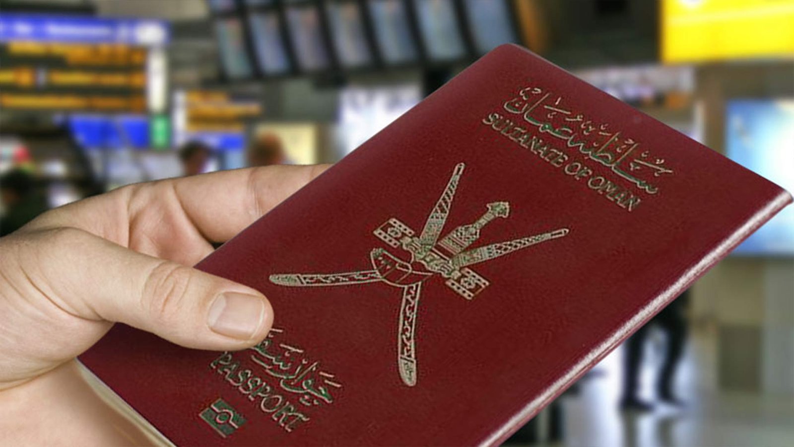 A hand holding an Omani passport at an airport, symbolizing travel and the importance of understanding Oman visa requirements for international entry into the Sultanate.