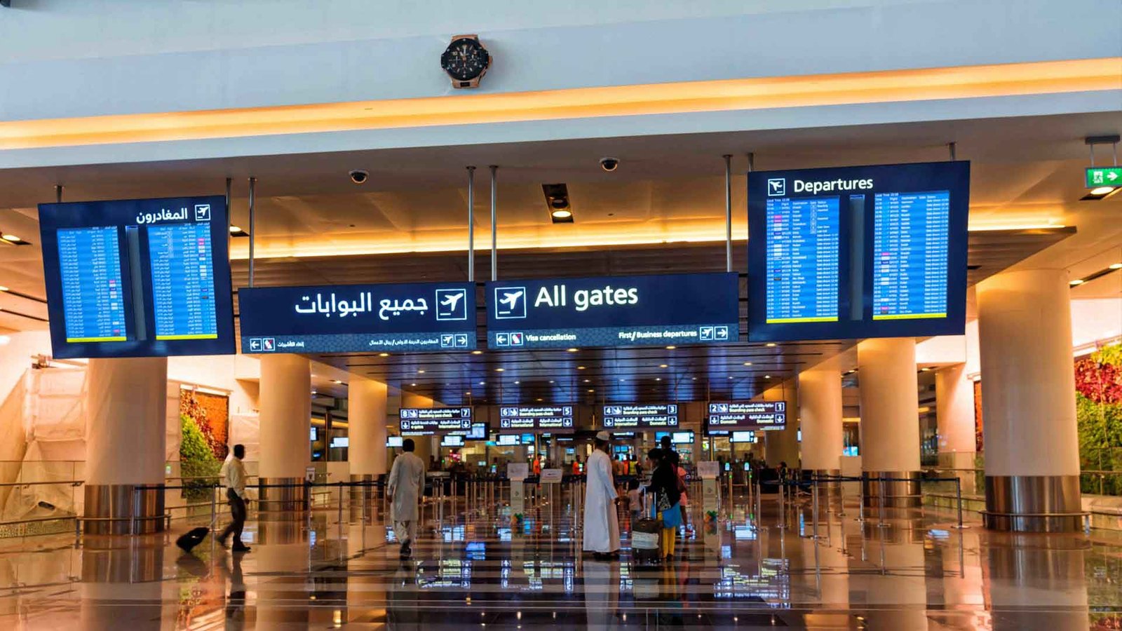 ravelers walking through an airport departure area with gate information displayed, emphasizing the importance of understanding Oman visa requirements before embarking on international travel to the Sultanate.