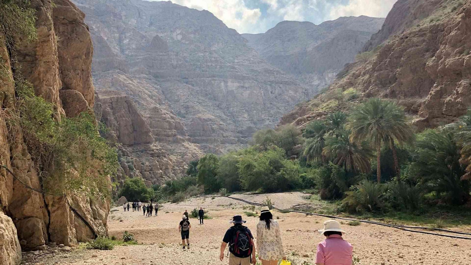 Hikers walking through the rocky Oman Hiking Trails landscape of Wadi Shab Oman